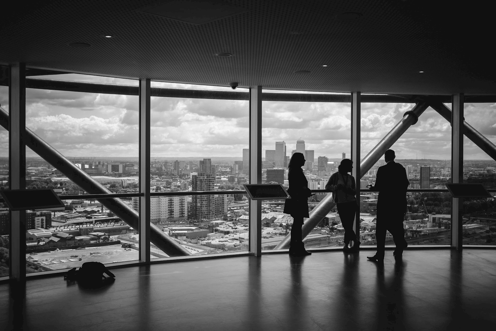 Three people in a high-rise with a cityscape view. Credit: Charles Forerunner, Unsplash.